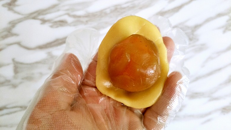 广式月饼,饼皮压扁,包住馅料,虎口收口