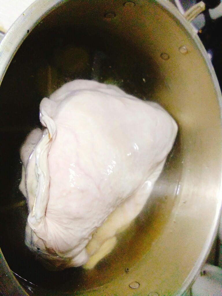 家常养胃荤菜 肚包鸡,锅的底部用筷子架成井字形状,防止粘锅。猪肚包鸡压在上面。加凉水没过猪肚,加入剩余姜片,大火烧开。