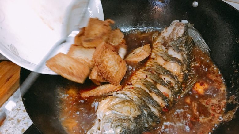 红烧鲤鱼,下豆腐,然后加盖焖煮大概两三分钟,这时一定要开大火,让鱼的汁水渗入豆腐,翻滚的汤汁也使鱼肉更入味