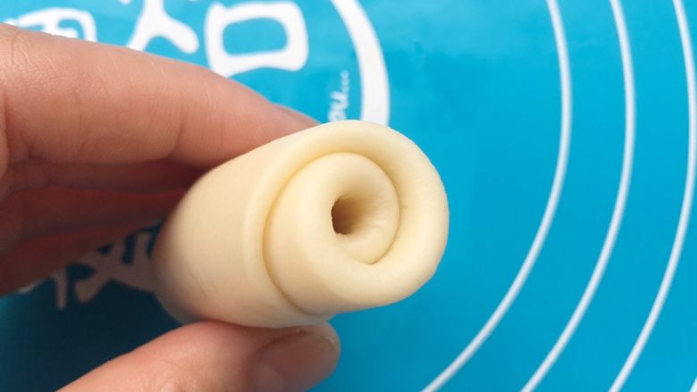 老婆饼,向一头卷起来。重复用擀面杖擀成牛舌状态,再卷起来。