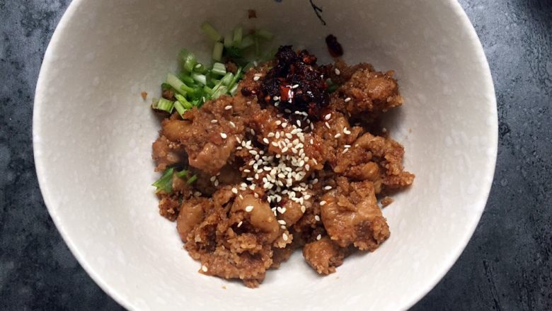 四川乐山名小吃—粉蒸肉卡饼,取适量粉蒸肉放入香菜小葱碗中,加入适量油辣椒,芝麻拌匀。