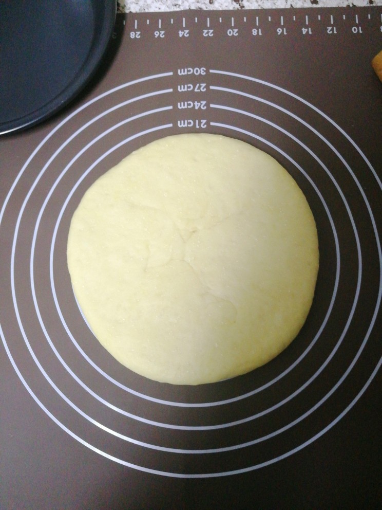 玉米培根披萨,发酵好的面团放在硅胶垫上揉成不沾手的面团（如果面团粘手可以散点面粉）