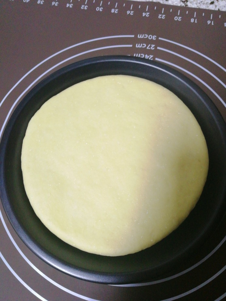 玉米培根披萨,用擀面杖把面团擀成与披萨盘一样大小的面饼，把面饼放入披萨盘。