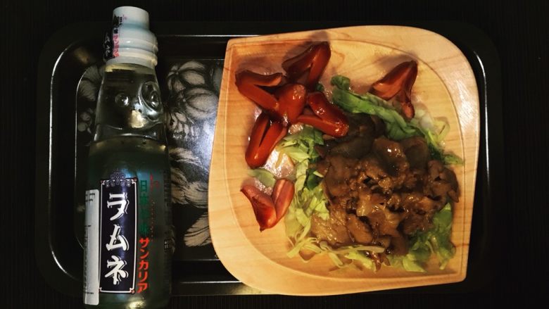 姜汁豚肉定食,在盘里铺上菜丝,放上猪肉片,淋上平锅里剩下的酱汁。煎好小热狗(可以加一个煎蛋)后盛盘。