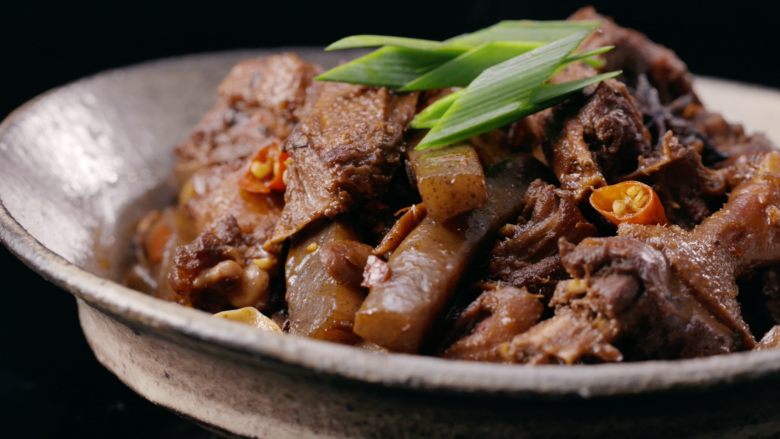 魔芋烧鸭,放入泡椒和蒜片,大火收汁,加少许盐调味,出锅装盘撒上青蒜苗,即可。