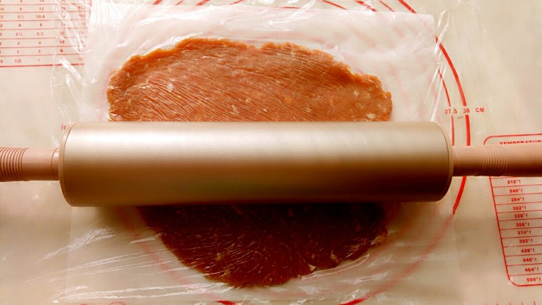 猪肉脯,取三分之一肉馅放到油纸上,上面盖上保鲜膜用阳晨金色擀面杖擀成2毫米左右的薄片。