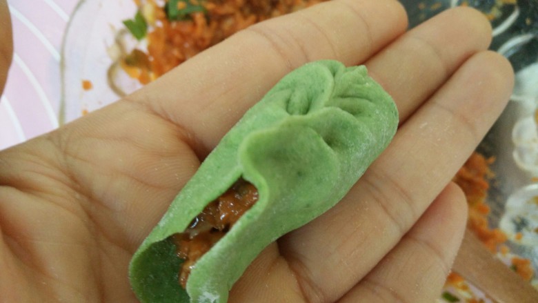绿叶饺子,取一个饺子皮,中间放上馅,食指拇指一起左右捏紧