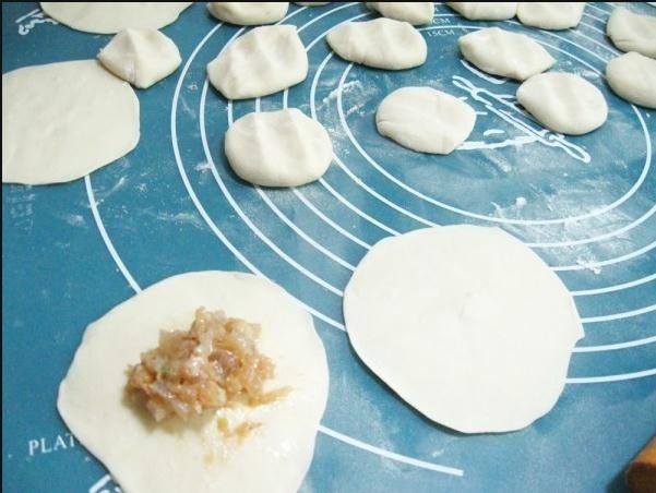美味灌汤包,用擀面杖把面团儿擀成中间稍厚四周薄的面皮,包入皮冻肉馅儿;