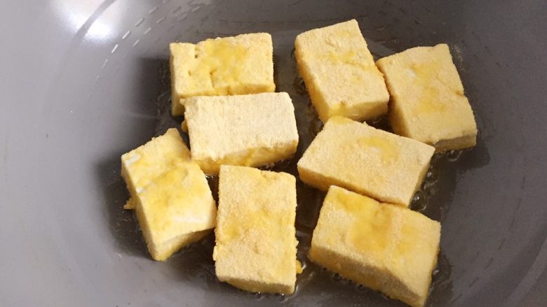 肉末豆腐,锅中倒入适量油烧热,放入沾上玉米粉的豆腐块,小火慢煎至皮稍硬,两面金黄后盛出,在盘中摆放好。
