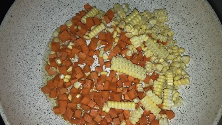 三文鱼三色蔬炒饭,另一个不粘锅加入油,放入胡萝卜丁和玉米粒,摊开后盖盖1-2分钟,直到胡萝卜变软。