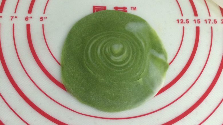 四色螺旋蛋黄酥,取一份切开的卷卷,用手掌压扁,再用擀面杖擀开,中间厚周围薄,中间的圈圈纹理部分尽量不要擀开。