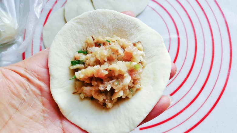 香菇肉包子,取一份面皮放在左手上,再放入适量肉馅;