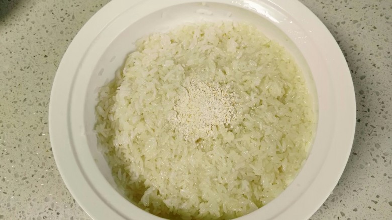 自酿米酒,降温到不太烫手就可以淋入400克纯净水。并翻拌至米粒湿润、温度接近体温。淋水的目的第一个是继续降温,第二个是使糯米米粒分明,但是千万不要搅成稀粥。并放入酒曲翻拌均匀。(余2克酒曲后续使用)