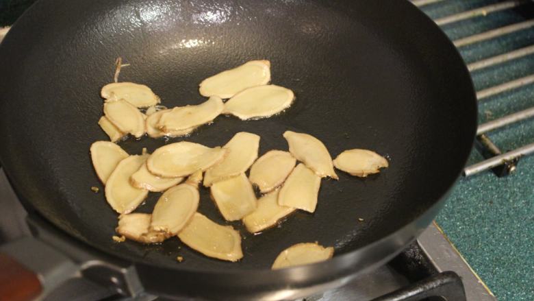 酒香麻油鸡油饭,先用白麻油2大匙将姜片小火慢慢煸香,煸至姜片快要卷曲。