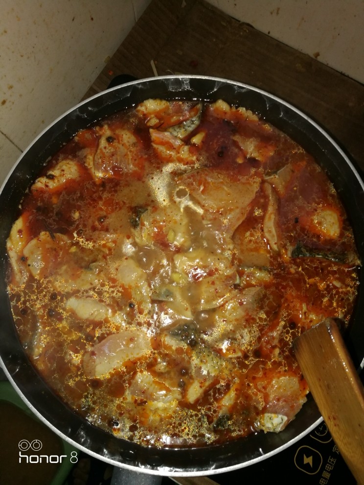 麻辣鱼,烹煮鱼片。期间可稍微翻动,待鱼片泛白,熟透后倒到刚刚准备好的锅底,女士小心汤汁溅到