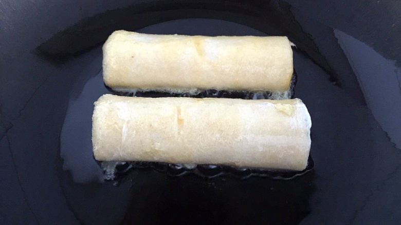 懒人料理-香蕉派,锅中放入适量的油,粘好鸡蛋液的卷放入锅中。