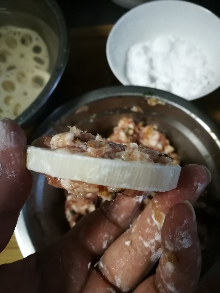 藕饼,藕片两面拍上一层生粉后,接着就放拌好的肉糜,用手取适量肉糜平整地轻轻按压在藕片一面的两边,很容易就粘住了,不用担心会掉。一面粘好肉糜再反过来粘另一面。(两手操作拍照片确实有点难度,只能文字陈述多一点😓)