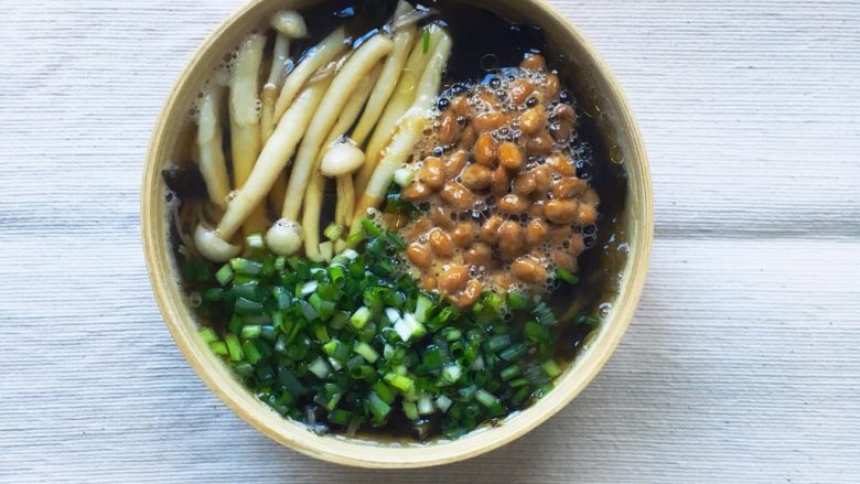 日式纳豆荞麦面,用碗乘放煮好的荞麦面和白玉菇,放上纳豆和葱花。