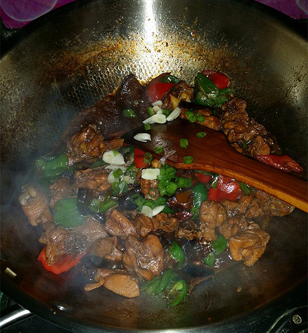 黄焖鸡,待青红椒变色后,最后撒入葱花和新鲜蒜瓣炒匀关火