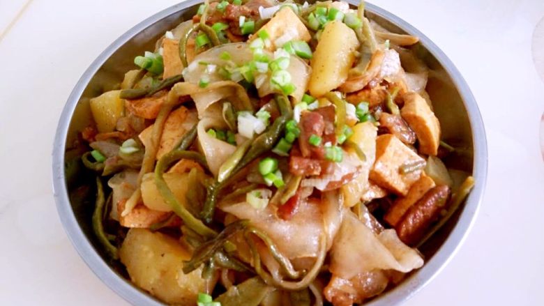 现猪肉烩干豆角,最后一步,看到土豆粉条变成透明状后,起锅撒上葱花就可以享用了。