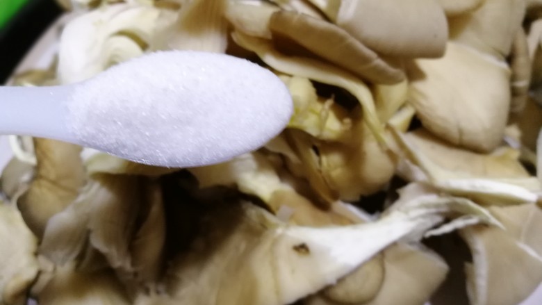 干炸鲜蘑,然后放入两勺盐用手轻轻抓匀,腌制一会。
