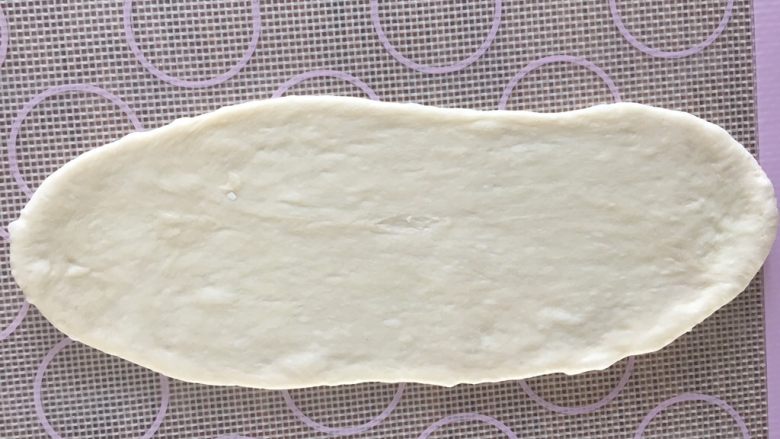 软萌面包卷(冷藏发酵),取一个松弛好的面团,用擀面杖从中间分别上下两边擀开;