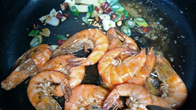 油焖大虾,虾炒红以后,铲到锅边,留个位置放入葱姜蒜和辣椒段炒香。