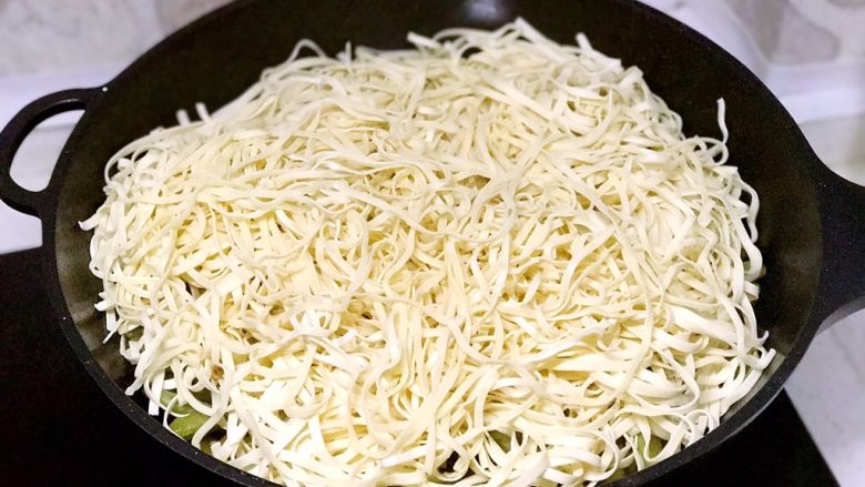 豆角焖面,把<a style='color:red;display:inline-block;' href='/shicai/ 526'>面条</a>均匀平铺到豆角上，盖锅盖，中小火焖面，计时5分钟；