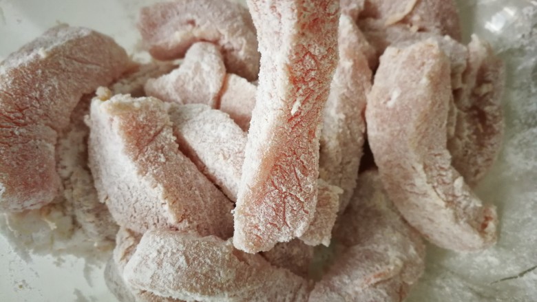 #糖醋菜#家常糖醋里脊,然后加入适量淀粉,每一条里脊肉都裹上淀粉。
