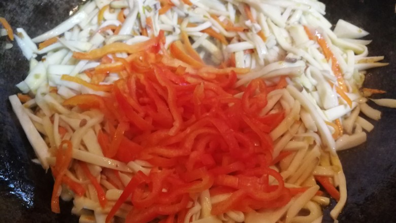 多彩素炒杏鲍菇,炒至杏鲍菇、胡萝卜条变软后,放入红椒条,翻炒一会儿。