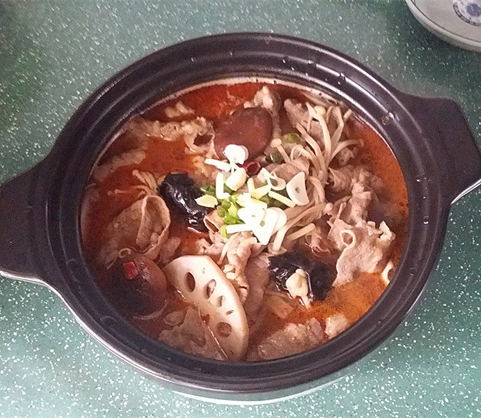 酱煮肥牛什锦锅,迅速连汤带肉一起倒入砂锅中,再撒些葱花和蒜片