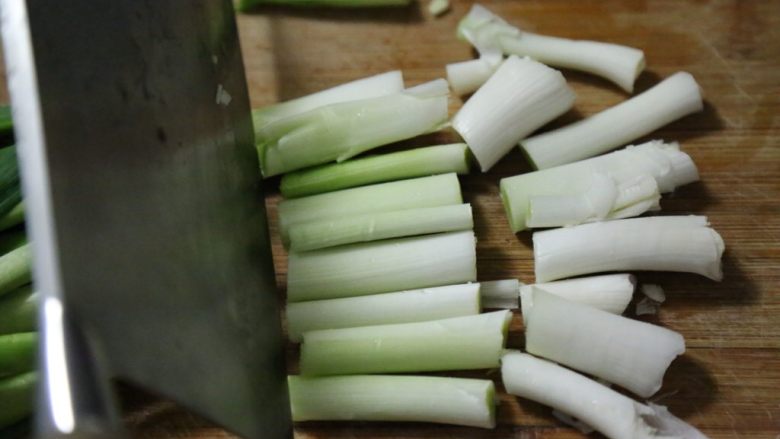 腊肠炒蒜,白色部分用刀拍松,切成长段。