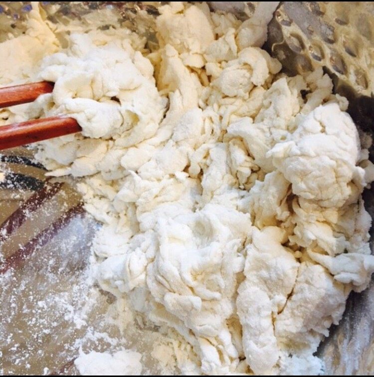 香酥羊肉馅儿饼,缓缓倒入温水,用筷子搅拌和面直至剩少量干粉,较软面团盖好醒一会儿备用