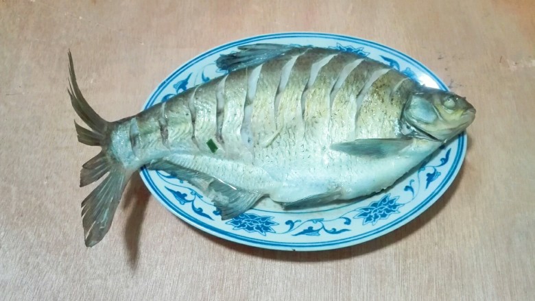 蚝白清蒸鳊鱼,蒸好取出来,倒掉盘子里面的水,去掉上面的姜片,葱白
