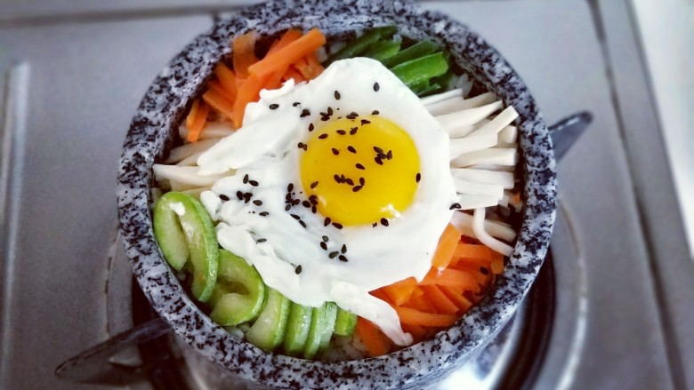 韩式石锅拌饭,将煎好的鸡蛋放入蔬菜上面，撒上少许熟黑芝麻，开小火大约3-5分钟，听到米饭发出滋拉滋拉的声音可以关火，锅底的米饭会有有一层锅巴，特别香。(一定要小火，一定要小火，一定要小火，重要的事情说三遍。）