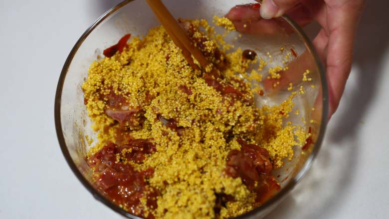 小米蒸排骨,将小米倒入腌制的排骨肉中,搅拌均匀
