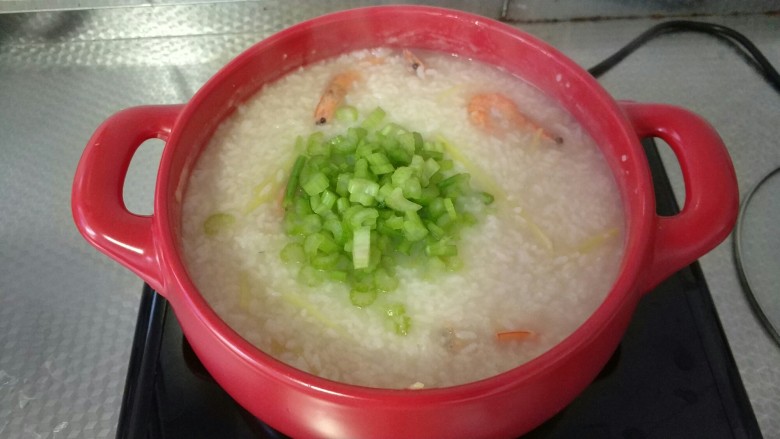鲜虾白米粥,此时锅中的米已经变得粘稠,米粒已煮开,在锅中加入切好的芹菜,在锅中加入适量的盐,此时如果锅中的水少,可以适量添加一些水。
