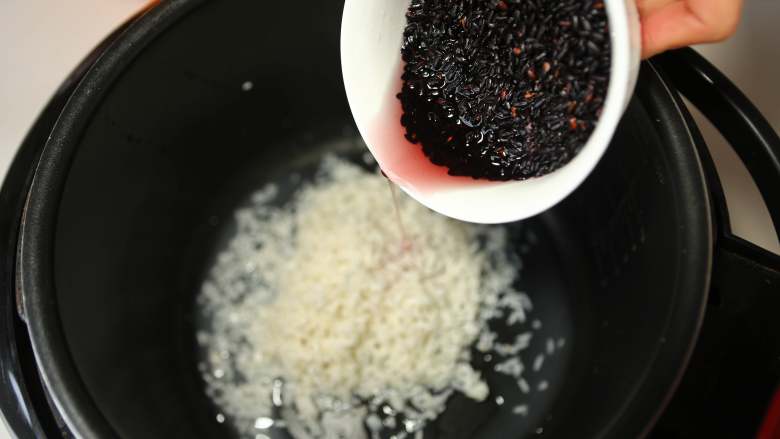 美味甜点-芒果黑米甜甜,将泡好的黑米、白糯米一起放入电饭煲中,加入水,按下煮饭键