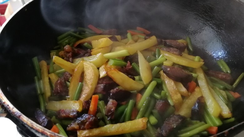 腊肠炒土豆条蒜苔,加土豆条翻炒,大火收汤。