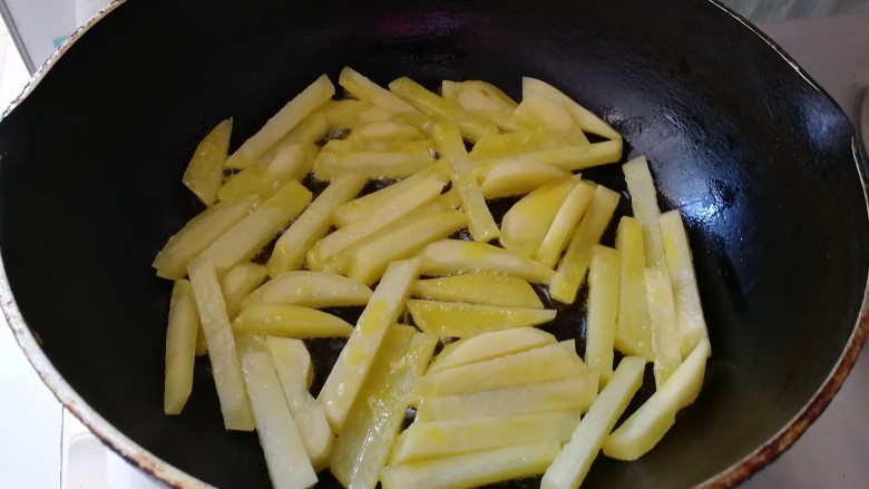 腊肠炒土豆条蒜苔,油热放入土豆条(油是平时炒菜的2倍)