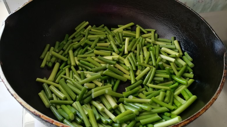 腊肠炒土豆条蒜苔,锅底留油,放入蒜苔翻炒。
