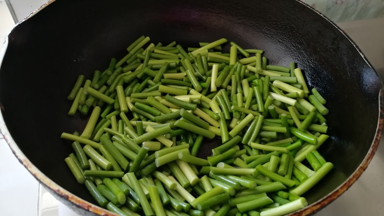 腊肠炒土豆条蒜苔,锅底留油，放入蒜苔翻炒。