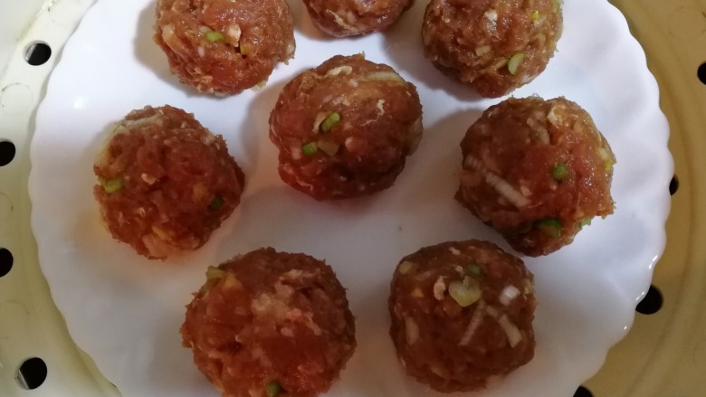 吉利蒸肉丸,把肉馅儿用手挤成丸子,码在盘中,放入蒸笼内蒸15分钟。
