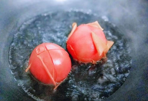 一碗面条+番茄鸡蛋打卤面,锅中加入清水,大火烧开后,加入划好十字刀的番茄,煮至皮裂开,捞出即可。