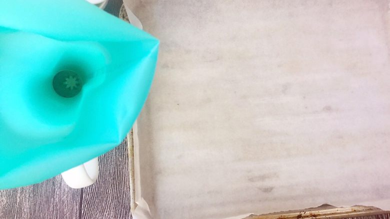 牛油果溶豆,这时候先不要着急下一步,先把烤盘铺好油纸,这里说一下,一定要用油纸哦,不能用锡纸代替,因为到时候锡纸会粘的,另外裱花袋放在一个杯子里也准备好。