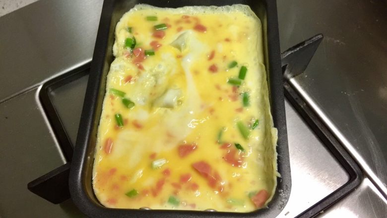 香葱火腿厚蛋烧,玉子烧锅刷一层油,烧热,保持小火慢煎,倒入部分蛋液,煎成蛋皮。