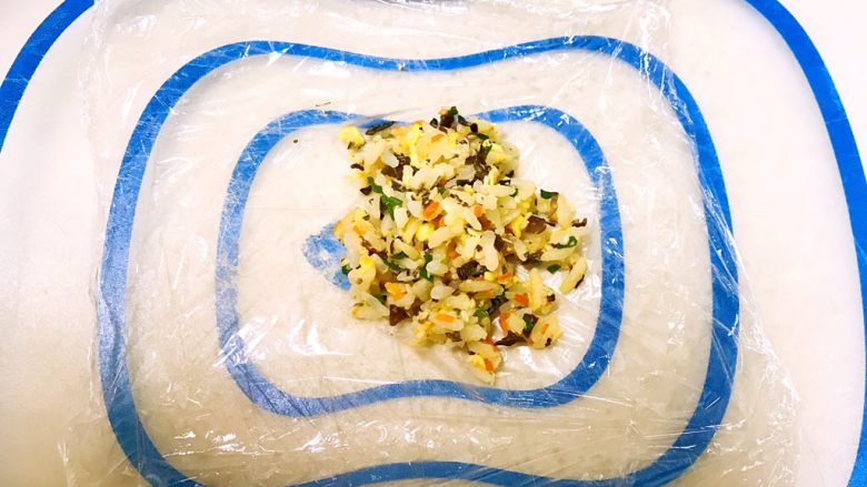 甜虾饭团,取一片保鲜膜,在保鲜膜上放入一勺炒饭