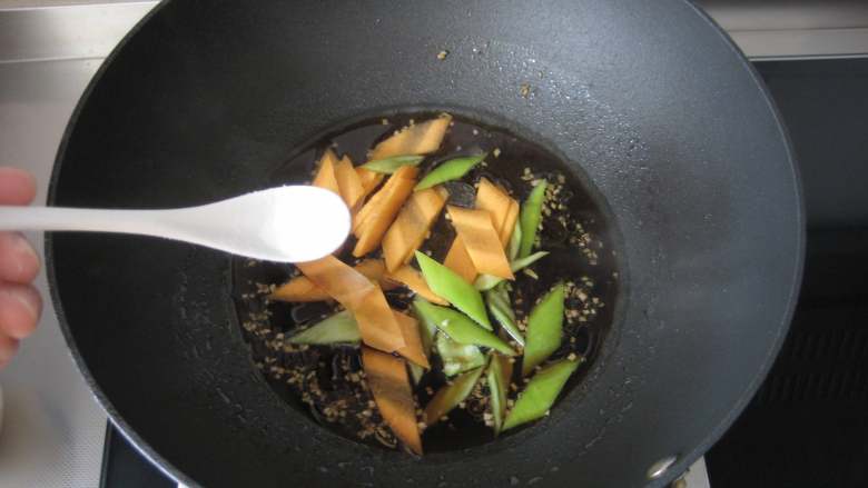 焦溜素肉,放入胡萝卜片和尖椒片,加盐、糖略煮。
