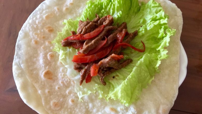 嫩牛肉卷饼#感恩节食谱#, 在饼上放上已经的生菜叶,再放上适量炒好的牛肉条。