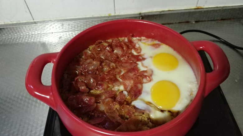 广式腊肠煲仔饭,当水分快要吸干,大米还略微冒泡的时候,可以把腊肠片放入,打两颗<a style='color:red;display:inline-block;' href='/shicai/ 9'>鸡蛋</a>。继续小火焖8分钟。